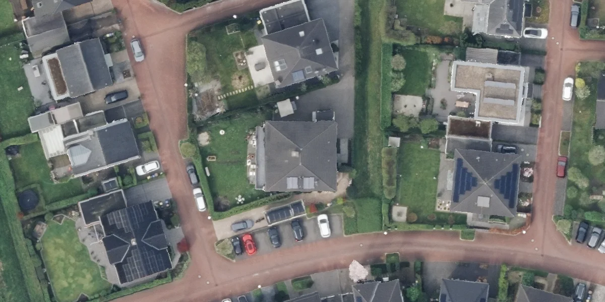 Senkrechtes Luftbild einer Wohnsiedlung mit freistehenden Einfamilienhäusern, Straßen und Gärten.