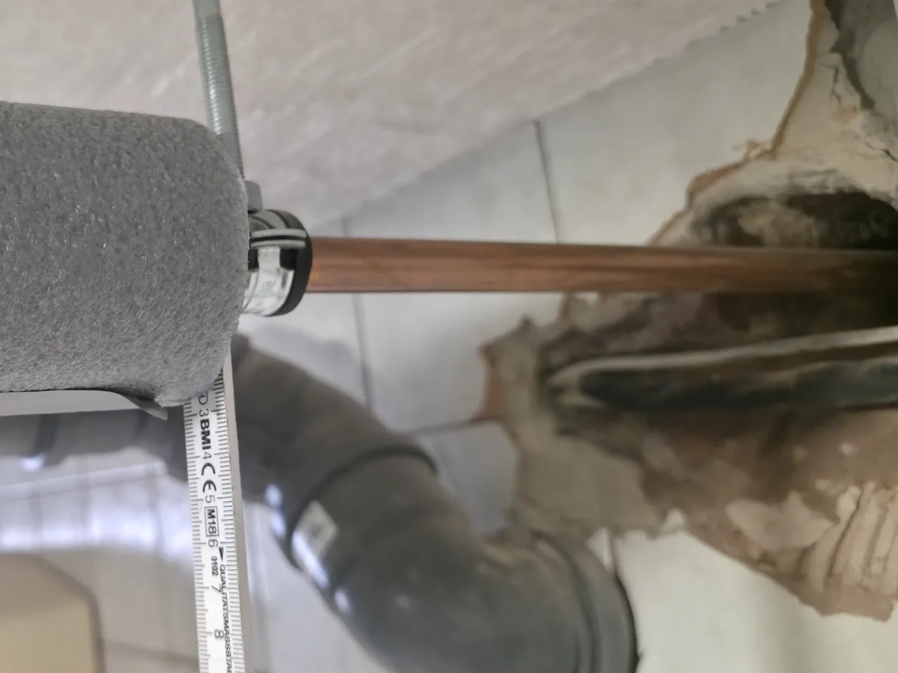 Eigenes Foto: Dämmung einer Warmwasserleitung endet vor einer Wanddurchführung, das Kupferrohr läuft blank in den Wandschlitz